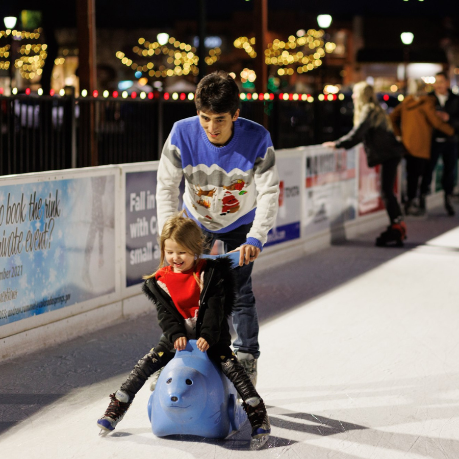 Man teaches child to ice skate.