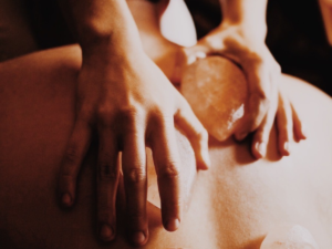Two hands giving massage with hot stones
